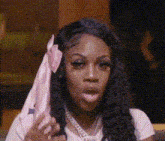 a woman is holding a pink ribbon in her hair and making a funny face .