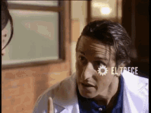 a man in a white lab coat is talking to a woman in a room .