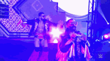 two wrestlers are walking on a stage with a w logo in the background