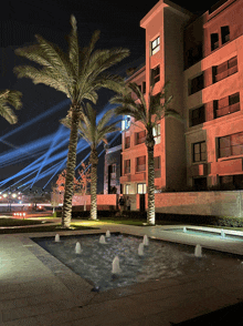 palm trees in front of a building with a fountain