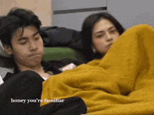 a man and a woman are laying on a bed under a yellow blanket .