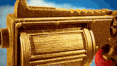 a close up of a gold toy gun with a red barrel