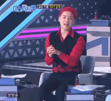 a man with red hair is sitting in a chair in front of a sign that says top7