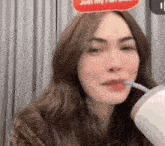 a woman is drinking from a cup through a straw .