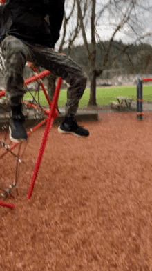 a person is sitting on a red ladder in a playground