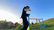 a man in a black shirt and black pants is standing in front of a swing set