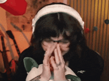 a woman wearing headphones and a ring is covering her nose