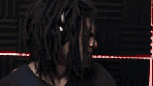 a man with dreadlocks is standing in front of a red light