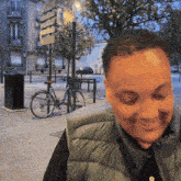 a man in a vest is smiling in front of a bicycle and a sign that says ' a ' on it