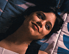 a woman is laying on a bed and smiling