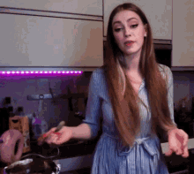 a woman in a blue and white striped shirt is cooking in a kitchen