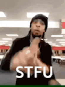 a man is giving the middle finger and the word stfu is on the bottom of the image .
