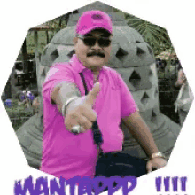 a man wearing a pink shirt and a pink hat is pointing at the camera .