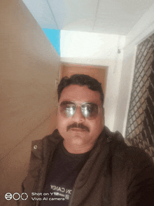 a man wearing sunglasses and a t-shirt that says yohad on it takes a selfie