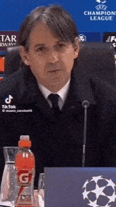 a man sitting in front of a microphone with a bottle of gatorade in front of him