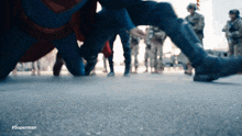 a person in a superman costume is kneeling down in front of a crowd of people