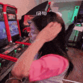 a woman adjusts her hair in front of an arcade machine that has the word midway on it
