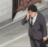 a man in a suit and tie is rubbing his eyes