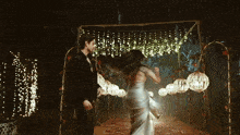 a man and a woman are dancing under a canopy of lights at night