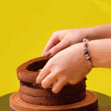 a person wearing a bracelet is cutting a piece of chocolate cake