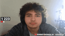a young man with curly hair is wearing headphones and has the number 1223 on his face