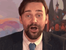 a man with a beard is wearing a suit and tie with his mouth open