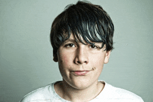 a young boy making a funny face with a white shirt on