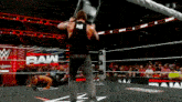 a man in a black tank top stands in a wrestling ring