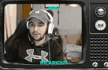 a man wearing headphones and an under armour shirt is on a tv screen .