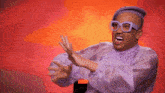 a man wearing a purple shirt and glasses is making a funny face .