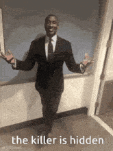 a man in a suit and tie is standing in a hallway with the words " the killer is hidden " behind him