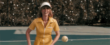 a woman in a yellow tennis outfit is holding a tennis ball and smiling