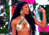 a woman wearing a gold bikini top and earrings is standing in front of a christmas tree .