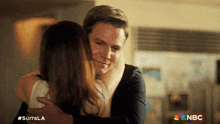 a man is hugging a woman with the nbc logo in the corner