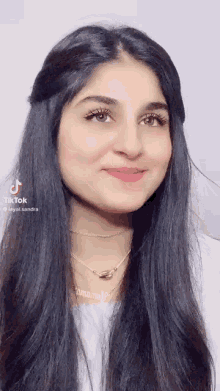 a woman with long black hair is smiling and wearing a necklace with the name sandra on it