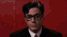 a man wearing glasses is giving an ok sign