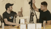 two men giving each other a high five in front of a camera