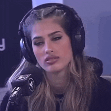 a woman wearing headphones is making a funny face while talking into a microphone .