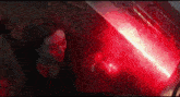 scarlet witch is looking at a red light in a dark room .
