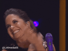 a woman with a purple microphone is smiling and has the hashtag lialmeida05