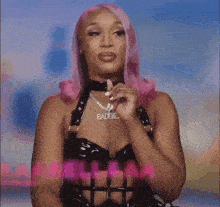 a woman with pink hair and a necklace that says baddies on it