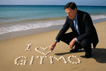 a man kneels on a beach writing the word gitmo