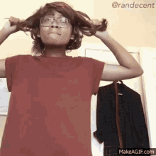 a woman wearing glasses is holding her hair in her hands .