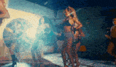 a woman in a bikini is dancing in a room with other people
