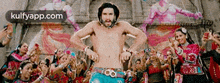 a man without a shirt is dancing in front of a crowd .