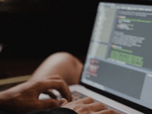 a person is typing on a laptop computer with a blurred background