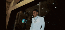 a young man wearing a white shirt and gloves is standing in front of a glass door .