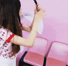 a woman in a pink shirt with cherries on it is standing in front of a pink wall