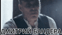 a man in a suit and tie is standing in front of a sign that says dmitry bandepa