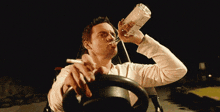 a man is drinking from a bottle and smoking a cigarette
